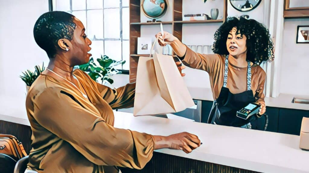 The Rise of Experiential Retail - black women, retail counter, cashier handing customer shopping bag over retail counter top